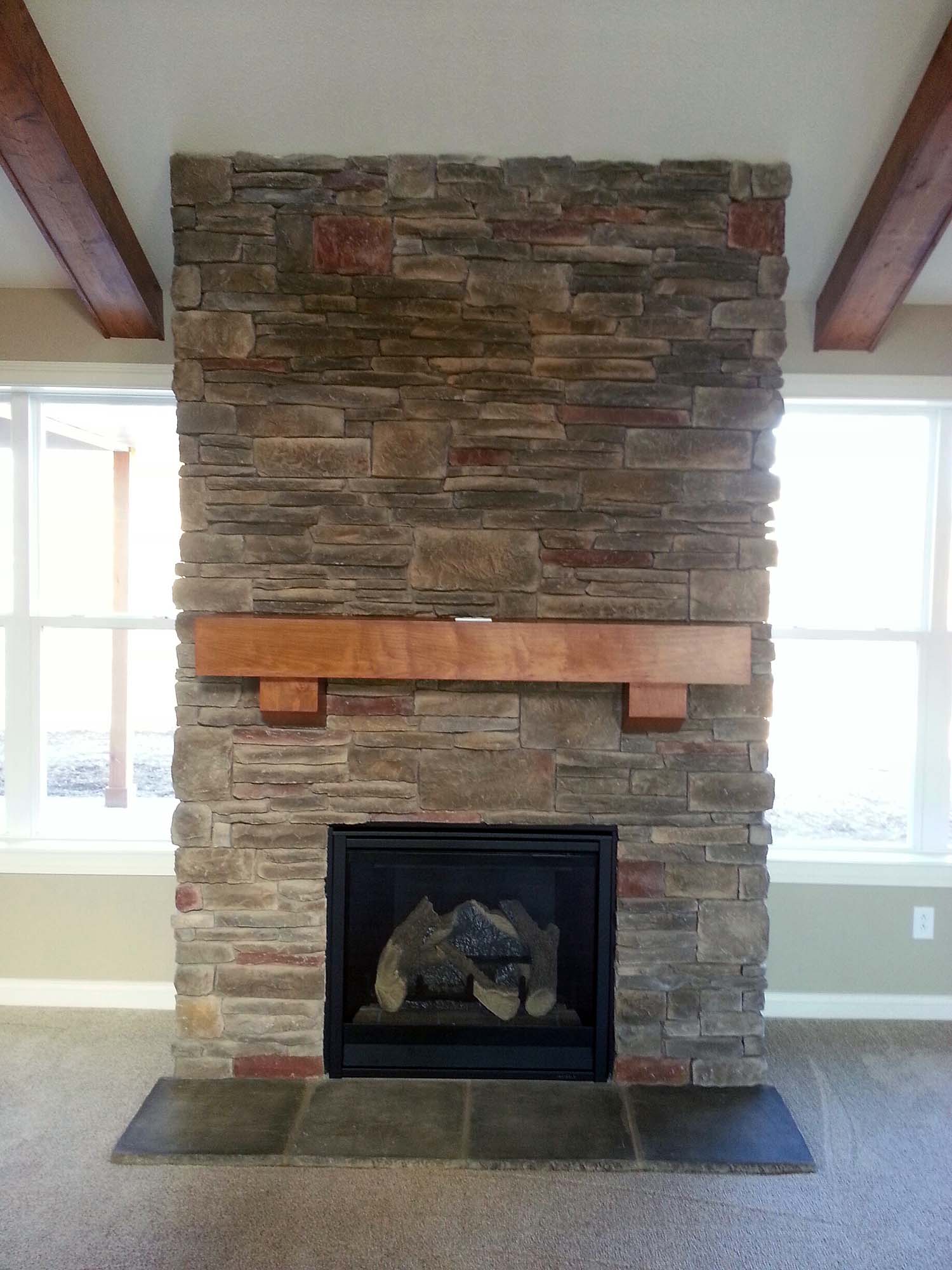 <p>Stone Veneer fireplace with distressed wood mantle</p>