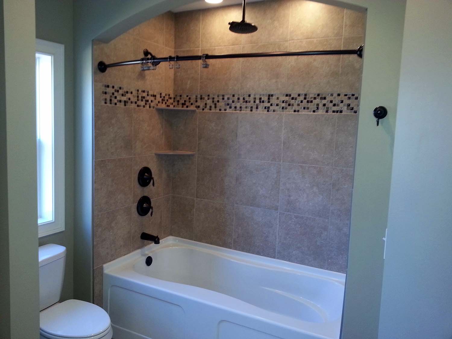 <p>Bathtub with tile shower walls and arched wall above</p>