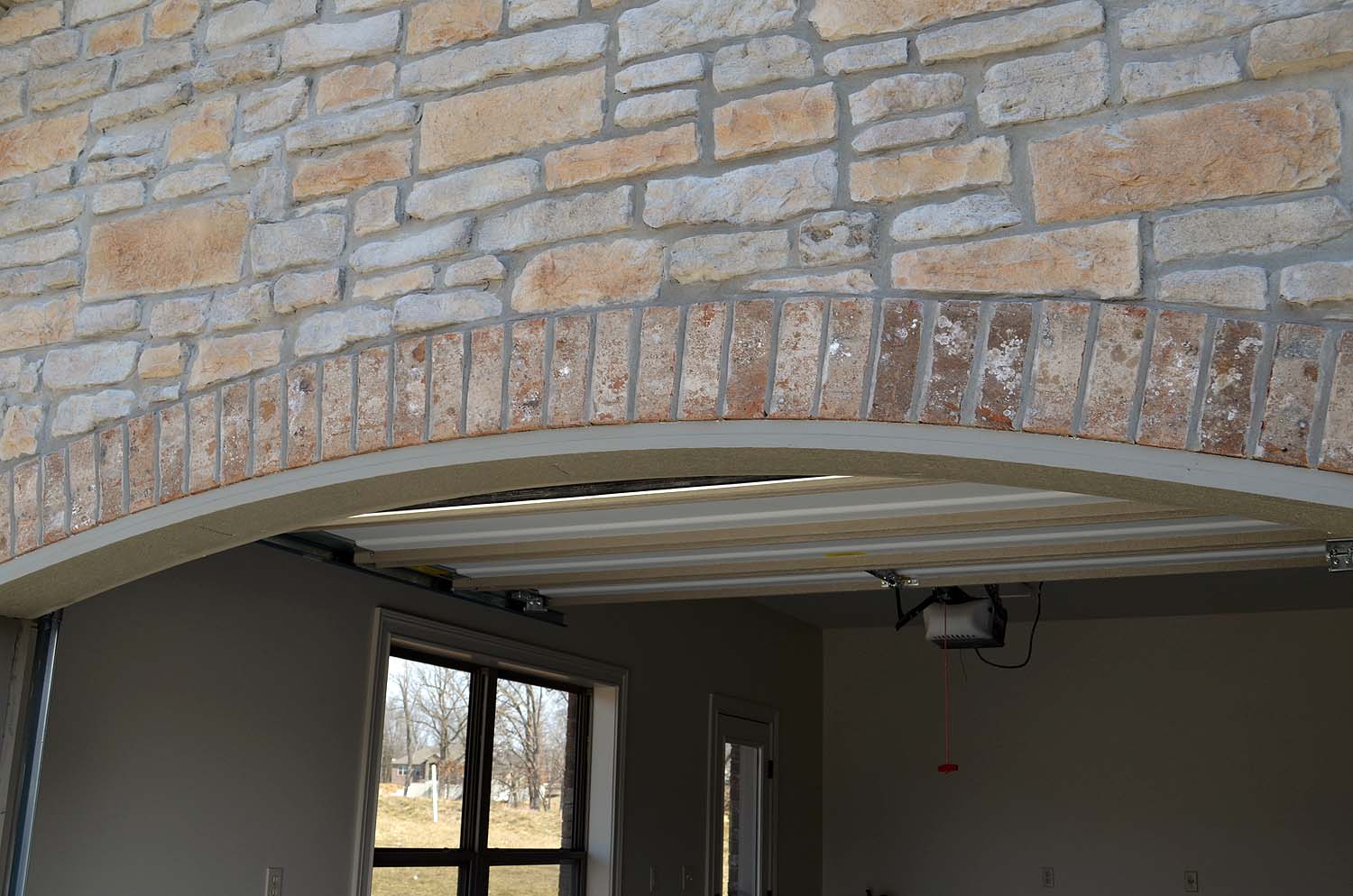 <p>Imitation stone with curved brick soldier course over garage door</p>